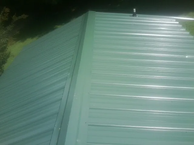 New green metal panels meeting at the ridge of a roof — Flat Roof Repair work by our crew in Novelty
