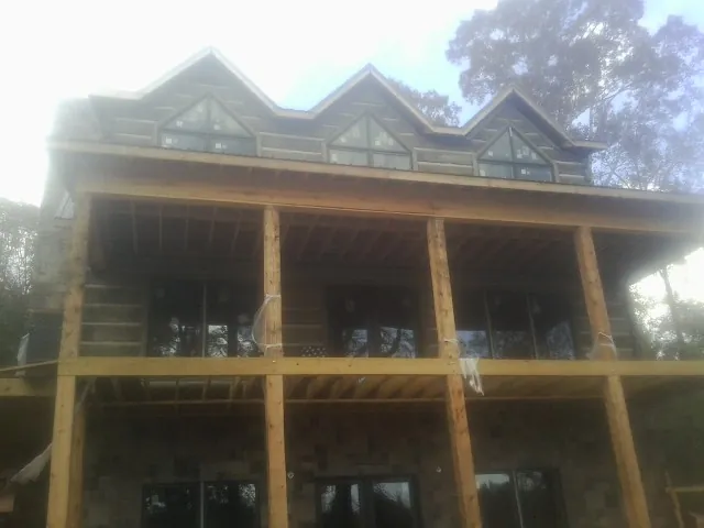 Dormers and porch framing on a large log home under construction — Roof Coating work by our crew in Novelty