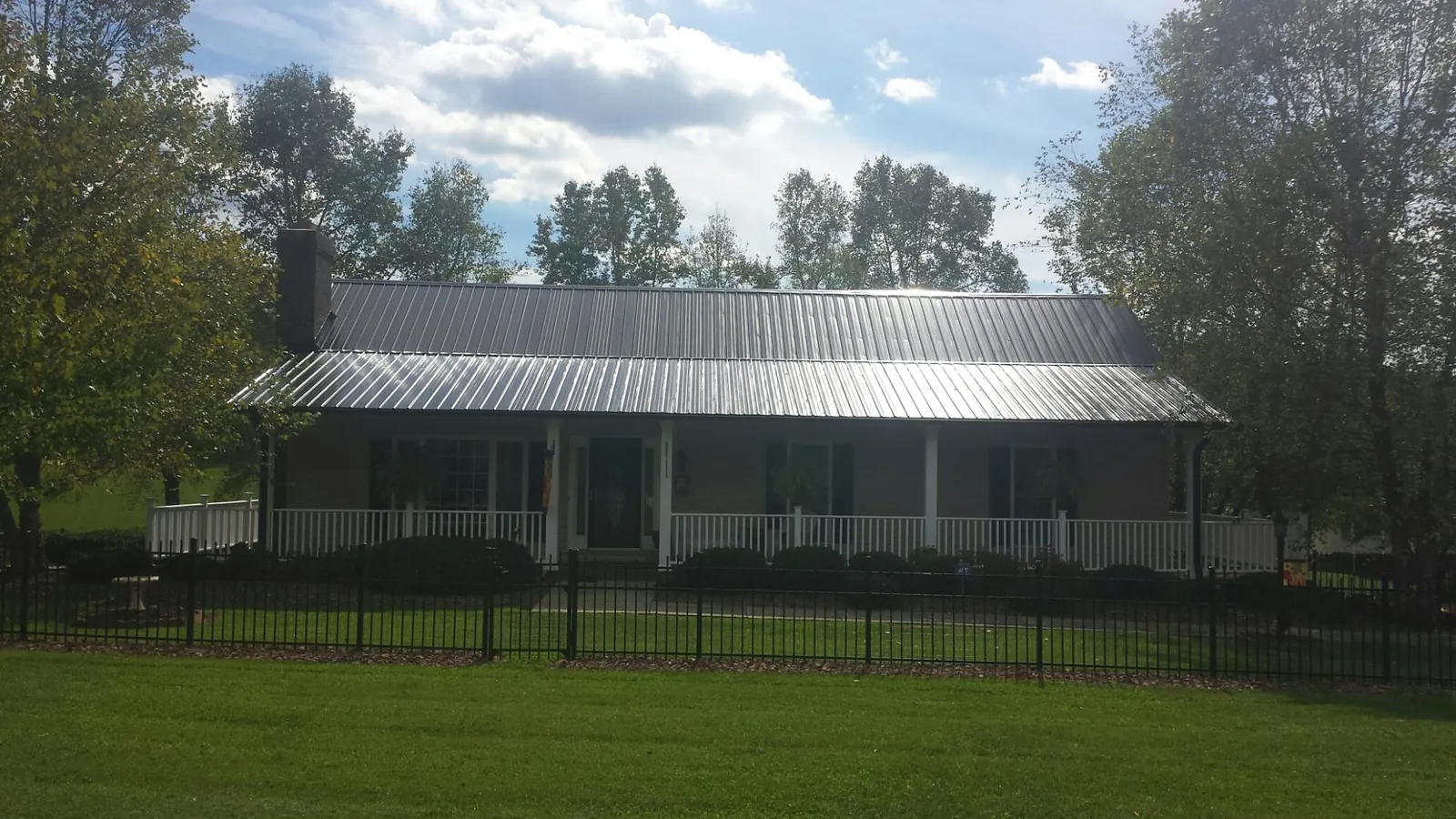 Gray metal roof on a brick ranch with a full width front porch — Gutter Guard Installation work by our crew in Novelty