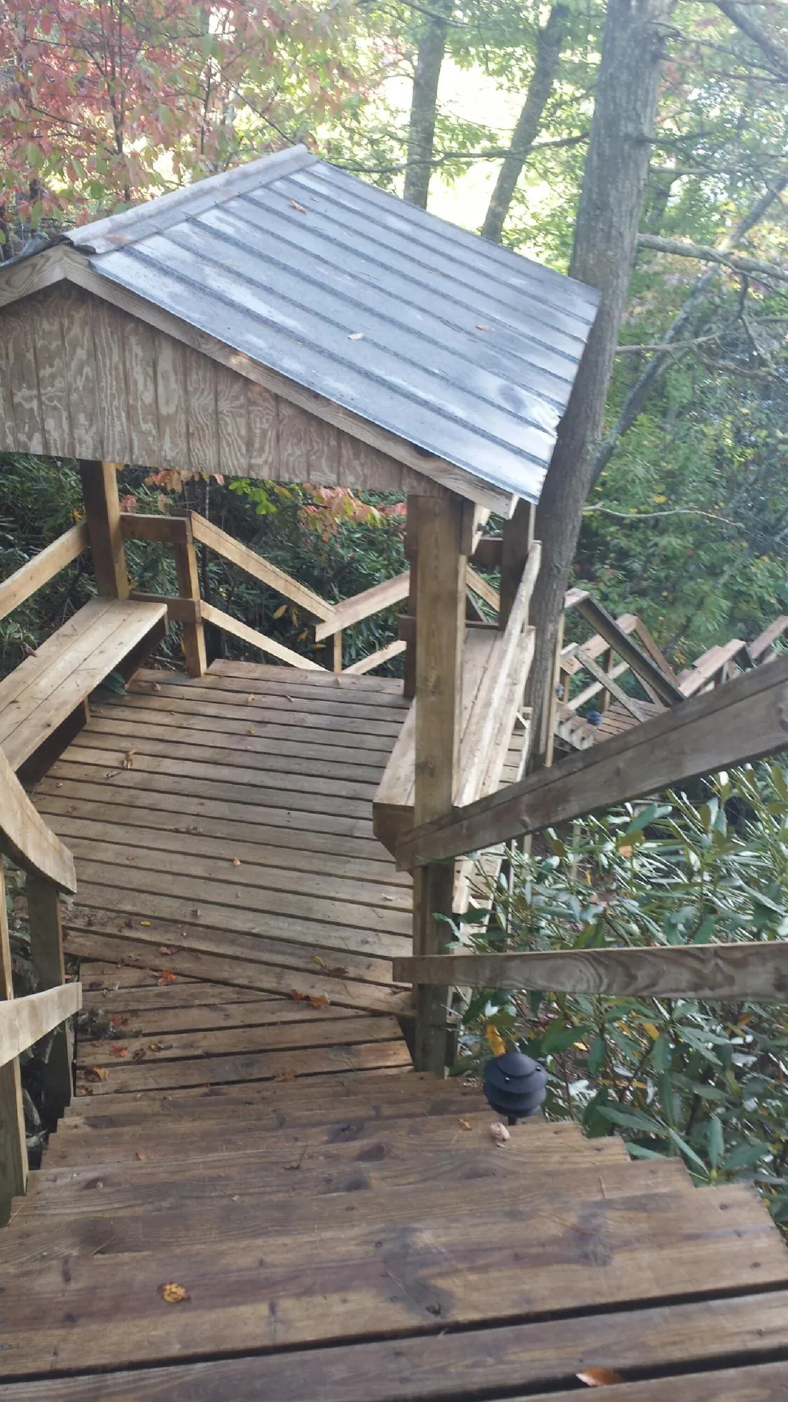 Metal roofed shelter over wooden steps on a wooded walkway — Skylight Repair & Installation work by our crew in Novelty