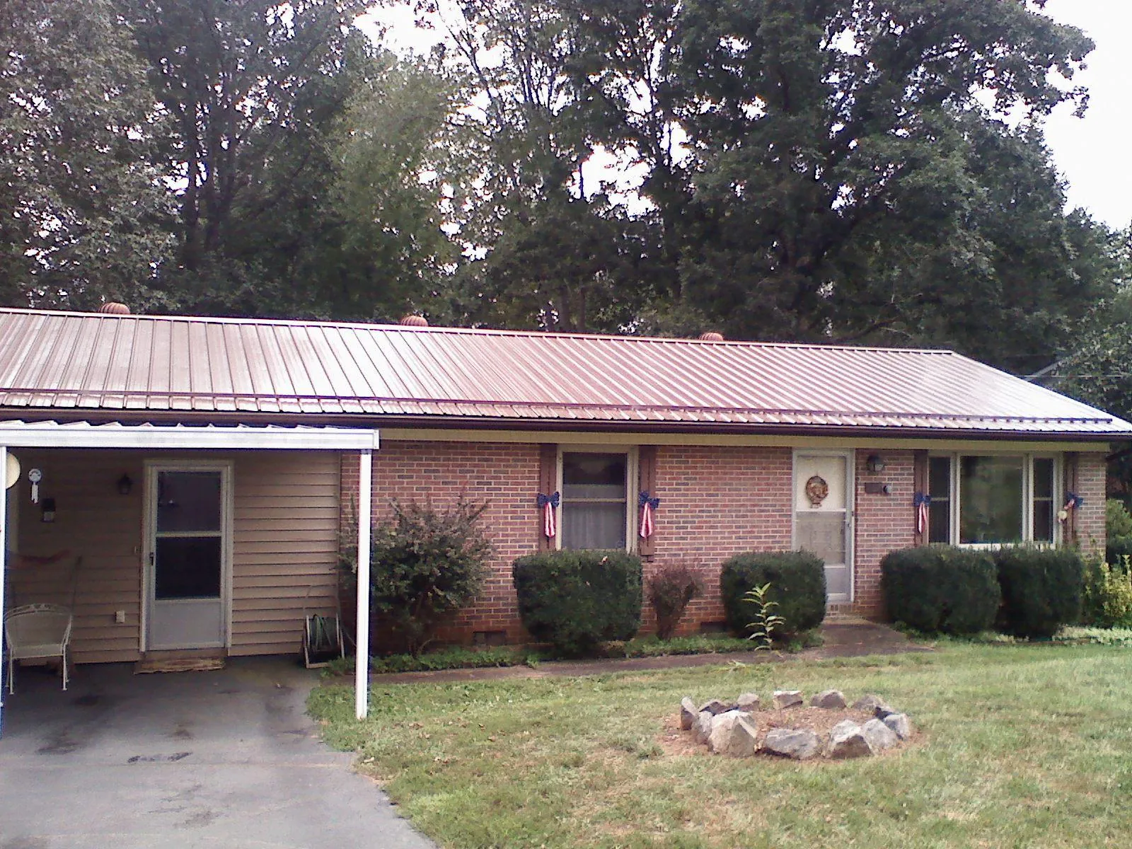 Bronze metal roof and carport on a brick ranch home — Roof Repair work by our crew in Novelty