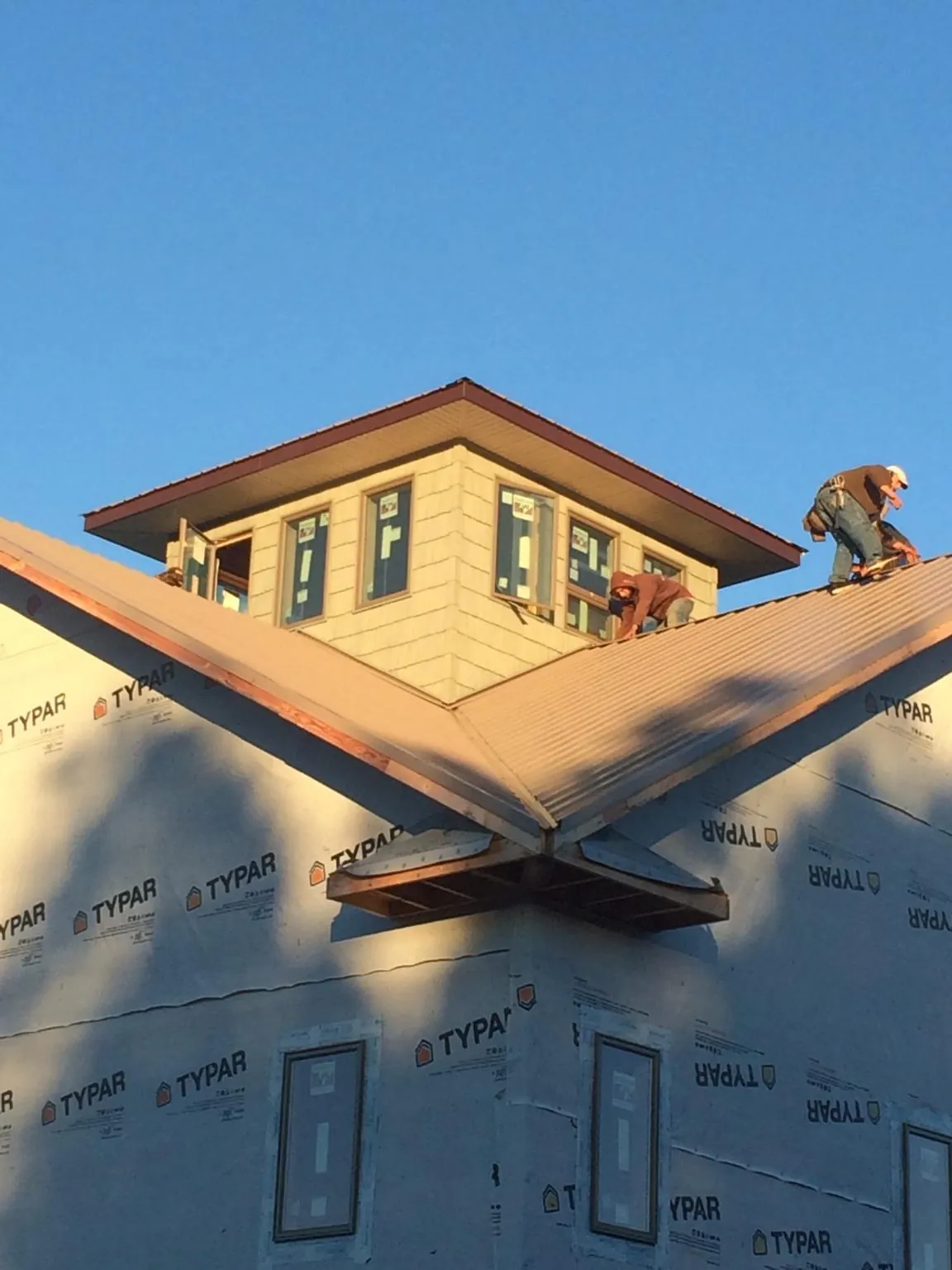 Roofers working around a rooftop cupola on a new metal roof at sunset — Roof Waterproofing in Novelty by Roofing Brothers